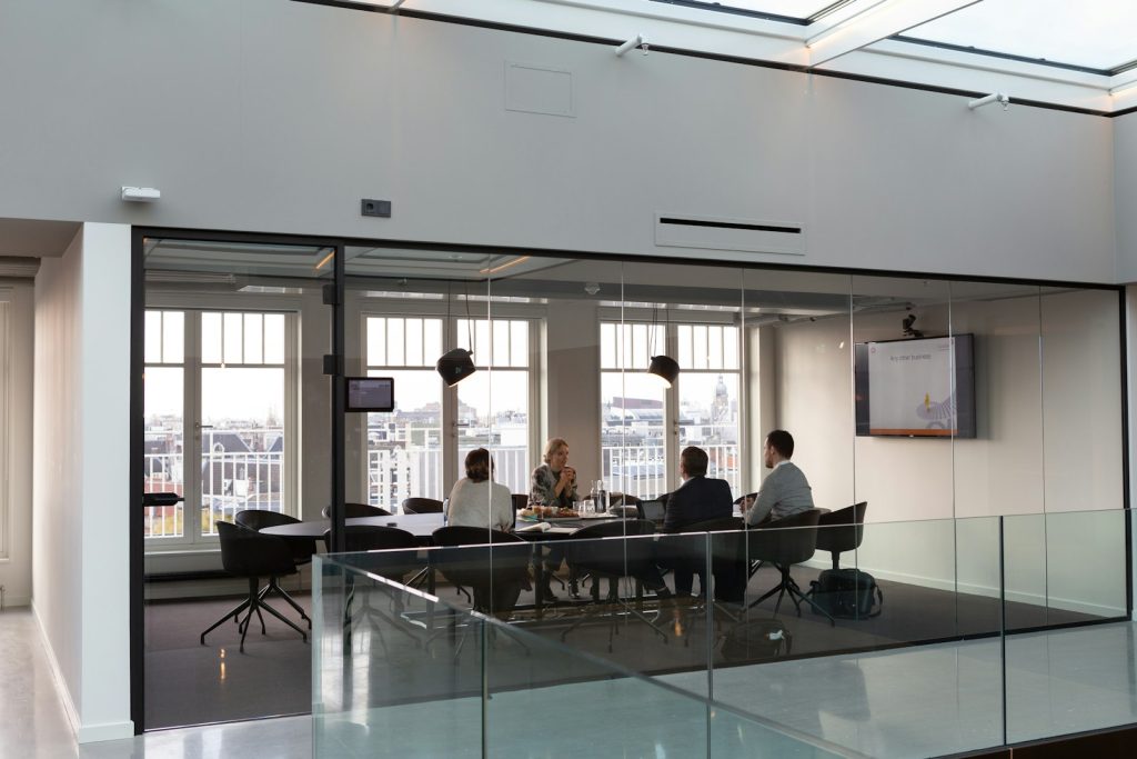 Petite équipe en réunion dans une salle vitrée d'un espace de coworking